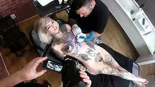 Sascha plays with Amber Luke while she gets tattooed